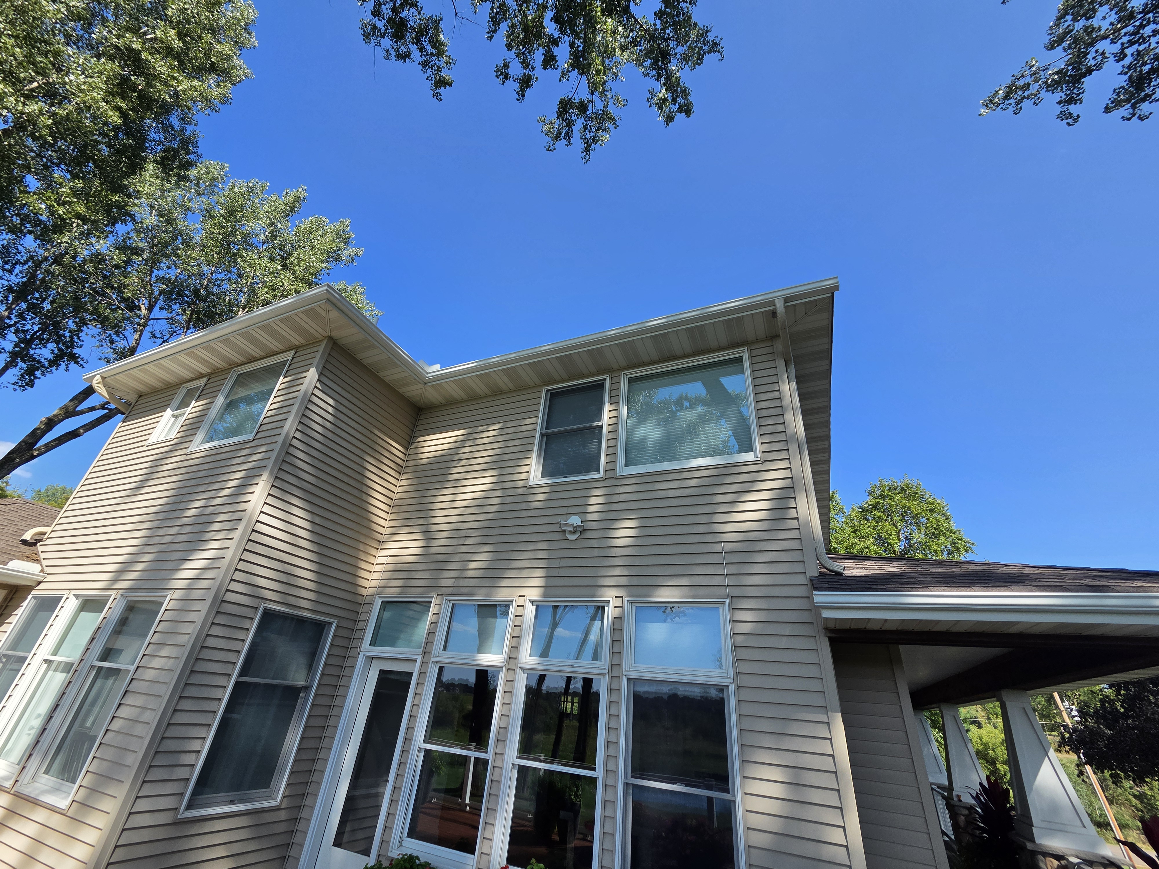 Upward view of siding, windows, and gutters on a two-story home