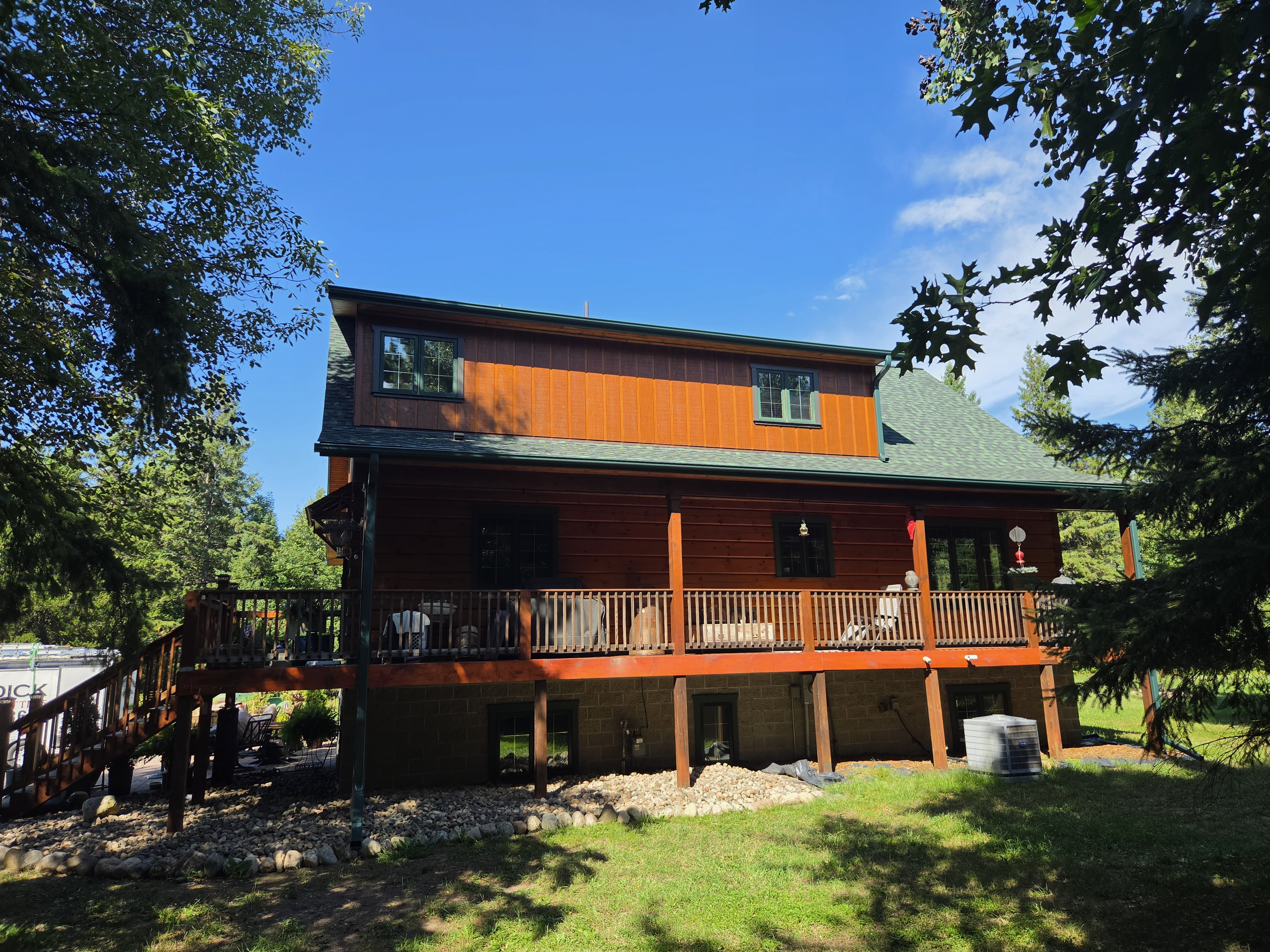 Rear view of a wood-sided home with a deck and gutters
