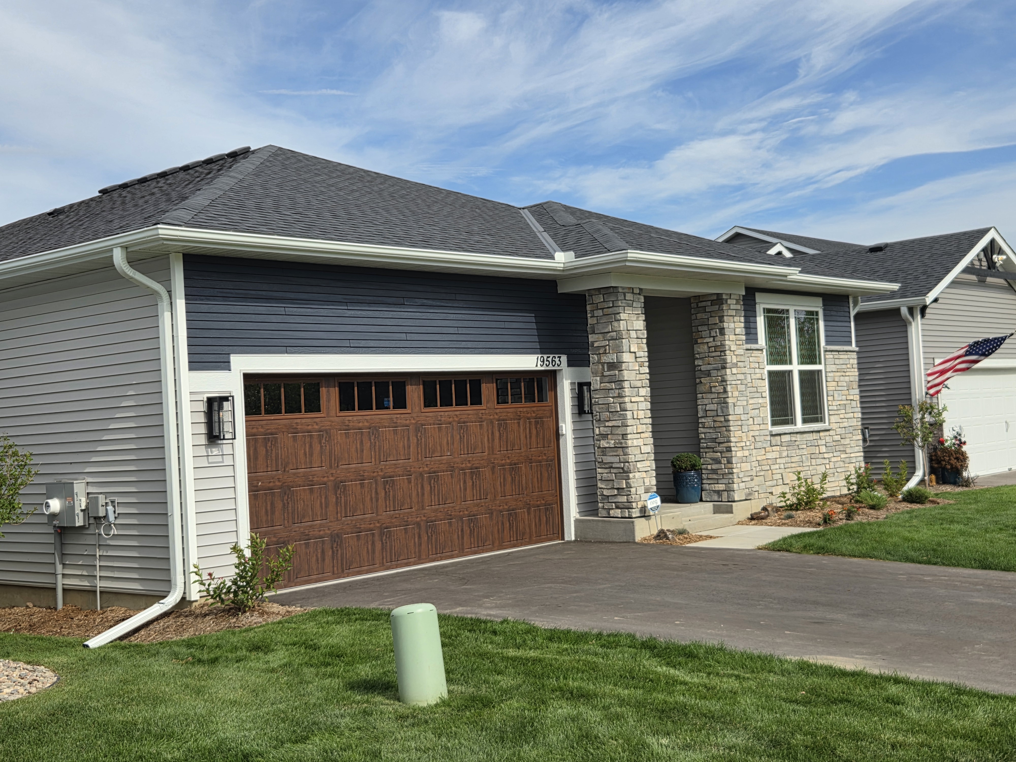 Gray-sided home with stone accents and white gutters