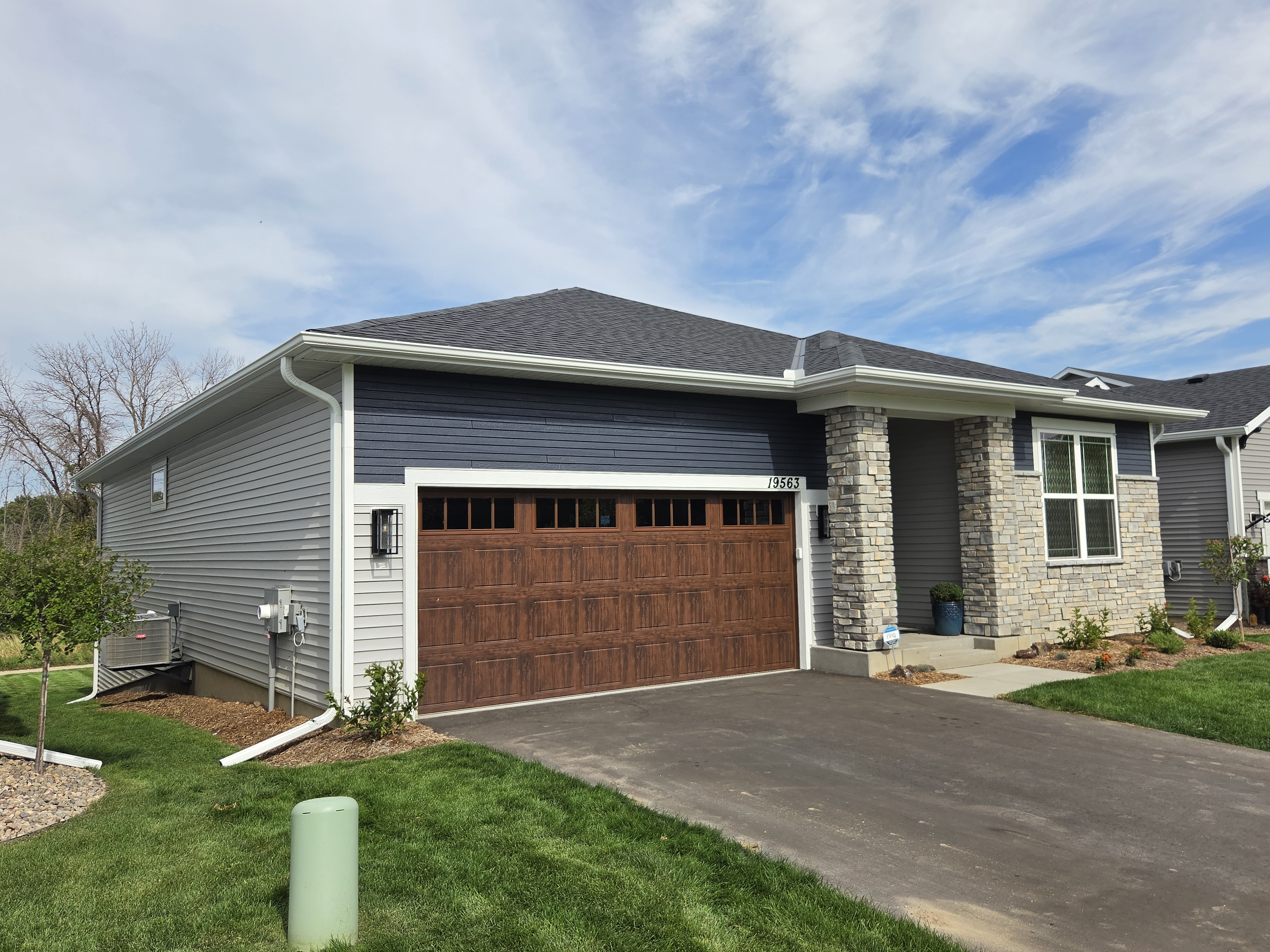 Angled view of white gutters and a downspout on a gray home