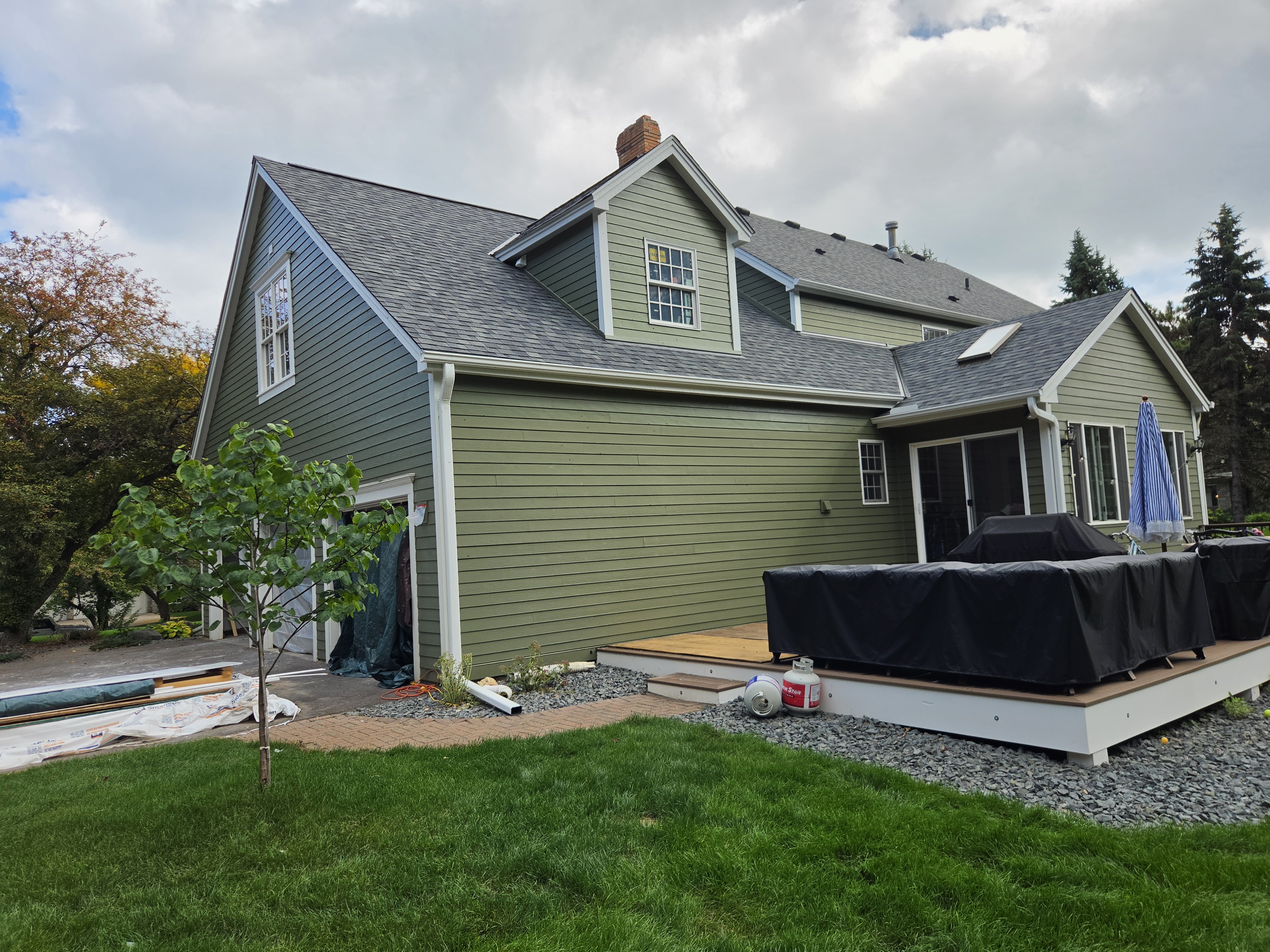 Rear view of a green-sided home with a deck and white gutters
